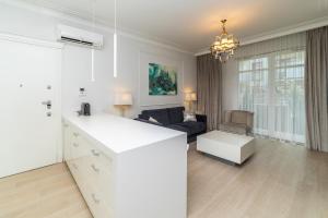 biała kuchnia i salon z kanapą w obiekcie Cristal - Neptun Park by OneApartments w Gdańsku