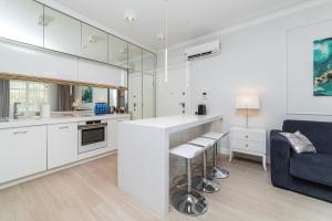kuchnia z białymi szafkami i niebieską kanapą w obiekcie Cristal - Neptun Park by OneApartments w Gdańsku