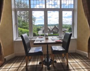 a table and two chairs in a room with a large window at The Knowe Guest House in Callander