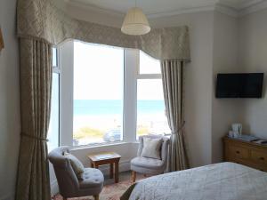 a bedroom with a large window with a view of the ocean at Frosty Towers in Llandudno