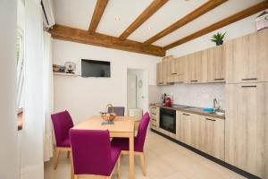 eine Küche mit einem Holztisch und lila Stühlen in der Unterkunft Santa Barbara Mljet apartment in Babino Polje