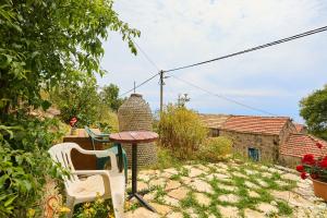 a patio with a table and chairs in a yard at Santa Barbara Mljet apartment in Babino Polje