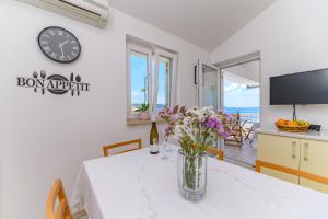 une salle à manger avec une table et une horloge murale dans l'établissement Apartmani Noris (app2), à Martinšćica