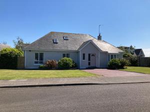 a white house on a street with a driveway at Links Close, Rosslare Strand, Ireland in Rosslare