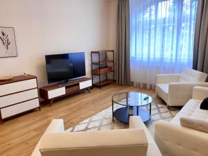 a living room with white furniture and a flat screen tv at Dobré časy Apartment in Poděbrady