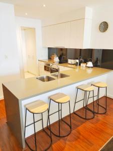 a kitchen with a counter with stools and a sink at Cscape3 in Cowes