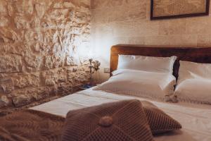 a bedroom with two beds and a stone wall at Le Cacinare in Modica