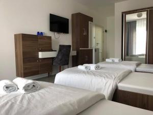 Habitación de hotel con 3 camas y espejo en Hotel Dardani, en Kosovska Mitrovica