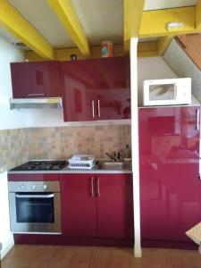 a kitchen with red cabinets and a white microwave at Maison bord de mer à St Gildas de Rhuys in Saint-Gildas-de-Rhuys