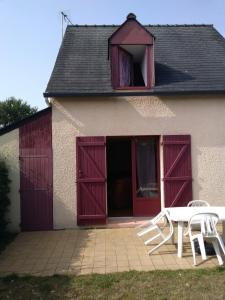 a building with red doors and a white table and a table at Maison bord de mer à St Gildas de Rhuys in Saint-Gildas-de-Rhuys