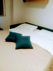 Una cama con almohadas verdes encima. en Blu Home en Crotone