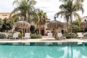 a swimming pool with chairs and palm trees at Can Sull in Caʼs Concos