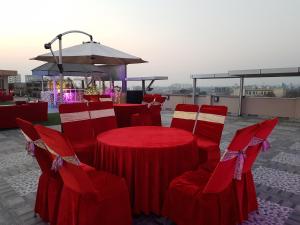 eine Gruppe roter Tische und Stühle und ein Regenschirm in der Unterkunft Maple Leaf Hotel in Kharar