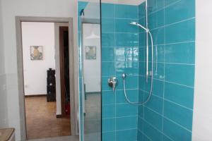 y baño con ducha de azulejos azules. en Villa Zagara, en Domus de Maria