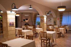 un restaurante con mesas blancas y sillas de madera en Hotel Costa D'Oro en Torre Ovo