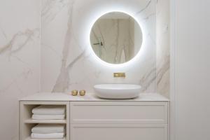 a white bathroom with a sink and a mirror at Plaza Apartments in Opatija