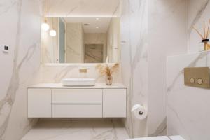 a white bathroom with a sink and a mirror at Plaza Apartments in Opatija