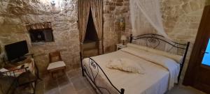 1 dormitorio con 1 cama en una pared de piedra en Il Trullo di Nonna Lella, en Castellana Grotte
