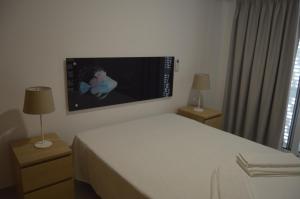 a bedroom with a bed and a flat screen tv on the wall at MORADIA NOVA E COMPLETA A 350 MTRS. PRAIA in Vila Nova de Cacela