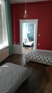 um quarto com uma cama e uma parede vermelha em Le Logis des Dames em Sedan