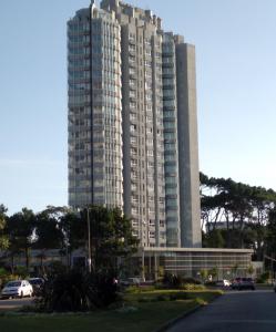 un edificio alto con coches estacionados frente a él en Vista Privilegiada, en Punta del Este