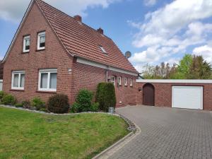 una casa de ladrillo rojo con garaje blanco en Ferienwohnung Am Ostfriesland-Wanderweg en Rhauderfehn
