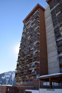 a tall building with a mountain in the background at Appartement Studio rénové le Corbier 4 personnes 22m2 domaine les Sybelles Classé 2 étoiles label qualité le corbier in Villarembert