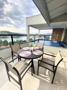 a black table and chairs on a balcony with a pool at Pousada Belvedere in Capitólio