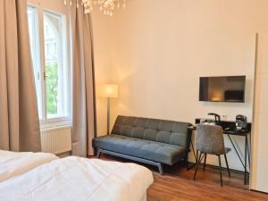 a bedroom with a couch and a desk and a television at Pension Mozart - Newly Renovated in Vienna