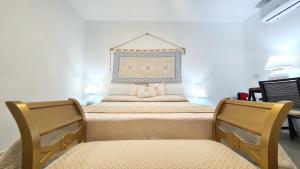 two beds in a room with two chairs at Sole Matto Rooms in Olbia