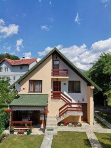 ein weißes Haus mit einem grünen Dach und einer Treppe in der Unterkunft Apartments Šćepanović in Kolašin