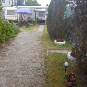 a garden path with a table and a blue umbrella at Caravans Magda in Niechorze
