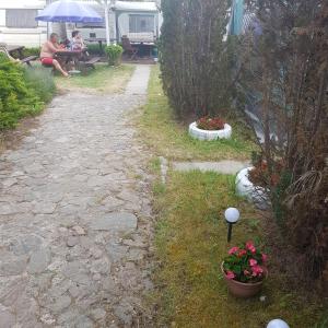 uma mulher sentada numa mesa debaixo de um guarda-chuva num quintal em Caravans Magda em Niechorze