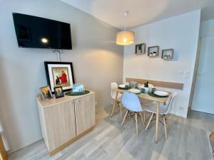 ein Esszimmer mit Tisch und Stühlen und einem Fernseher in der Unterkunft La suite new-yorkaise Disneyland Paris in Serris