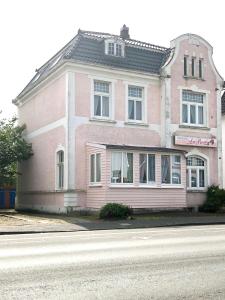 ein rosa Haus auf der Straßenseite in der Unterkunft Pension „La Rose“ in Norden