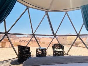 a room with a bed and three chairs in a tent at Zeina Desert Lodge in Wadi Rum