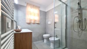 a bathroom with a toilet and a glass shower at Sole Matto Rooms in Olbia