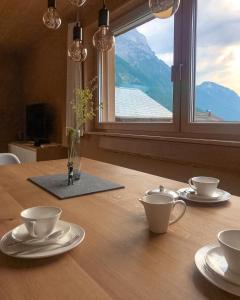 una mesa con dos tazas y platillos y una ventana en Ferienwohnung Schnepfau 24, en Schnepfau