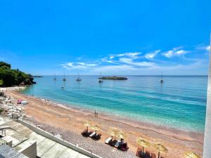 a beach with umbrellas and boats in the water at Plava Vila Beach Apartments Sveti Stefan in Sveti Stefan