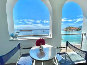 a table with a vase of flowers sitting on top of a window at Plava Vila Beach Apartments Sveti Stefan in Sveti Stefan