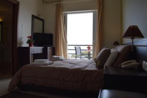 a hotel room with a bed and a large window at Tokalis Boutique Hotel & Spa in Nea Anchialos
