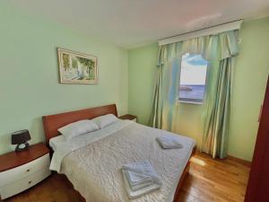a bedroom with a bed and a window with the ocean at Plava Vila Beach Apartments Sveti Stefan in Sveti Stefan