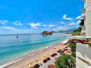 a view of a beach with umbrellas and the ocean at Plava Vila Beach Apartments Sveti Stefan in Sveti Stefan