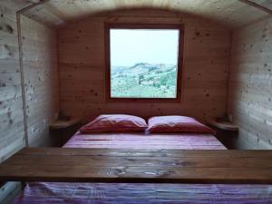 Cama en habitación de madera con ventana en La casetta sotto l'albero LA CAROVANA GITANA, en Vasto