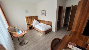 a bedroom with a bed and a table in a room at Schlosspark-Hotel Hof von Oldenburg in Rastede