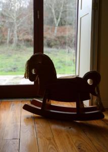 a wooden rocking horse sitting on the floor in front of a window at Quinta de Fermil - Casas in Vouzela