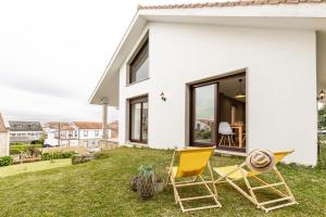 a white house with two chairs on the yard at Casa Clara in Isla de Arosa