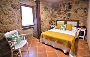 a bedroom with a bed and a chair and a window at Casa Rústica en Villagarcía de Arousa in Vilagarcia de Arousa