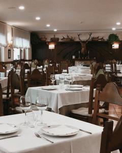 a restaurant with white tables and chairs with wine glasses at Hotel Rebeco in Fuente De