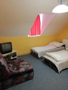 a room with two beds and a tv and a chair at Flamingó Étterem Szálláshely in Somlójenő